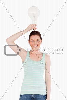 Cute red-haired female holding a bulb while standing