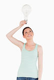 Gorgeous red-haired female holding a light bulb while standing