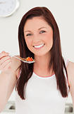 Good looking red-haired woman eating a strwaberry in the kitchen
