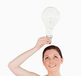 Gorgeous red-haired woman holding a bulb while standing