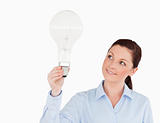 Gorgeous red-haired woman holding a light bulb while standing