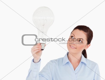 Gorgeous red-haired woman holding a light bulb while standing