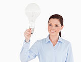 Attractive red-haired woman holding a bulb while standing