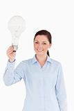 Good looking red-haired female holding a bulb while standing