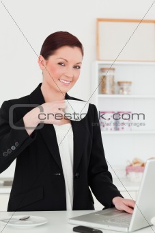 Beautiful red-haired woman in suit relaxing with her laptop whil