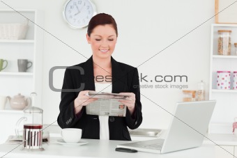 Pretty red-haired woman in suit reading the newspaper in the kit