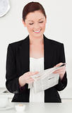Beautiful red-haired woman in suit reading the newspaper in the 