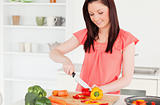Gorgeous red-haired woman cutting some carrots in the kitchen