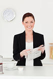 Attractive red-haired woman in suit reading the newspaper in the