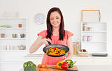 Pretty red-haired woman cooking vegetables in the kitchen