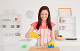 Pretty red-haired woman cleaning a cutting board in the kitchen