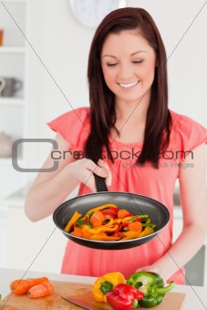 Attractive red-haired woman cooking vegetables in the kitchen