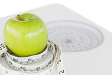 Closeup of a green apple circled with a tape measure and weigh-s