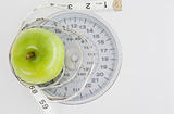 Green apple circled with a tape measure and weigh-scale