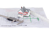 Toy house model and ruler and on a plan against a white backgrou