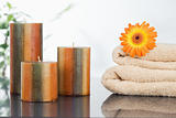 Unlighted candles with an orange gerbera on towels
