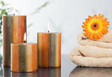 Lighted candles with an orange gerbera on towels