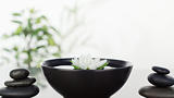 White flower floating in bowl in th ;iddleand two stacks of blac