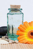 A glass flask with round smooth pebbles and a sunflower