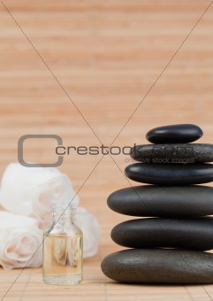Glass phial with roses and a stack of black pebbles