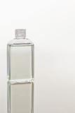 Glass flask on a mirror against white background 