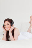 Beautiful red-haired female relaxing with her headphones while l