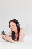 Gorgeous red-haired female listening to music with her headphone