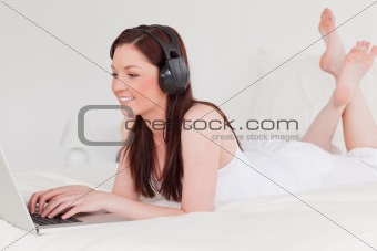 Good looking red-haired female relaxing with her laptop and her 
