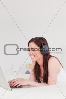 Pretty red-haired female relaxing with her laptop and her headph