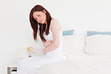 Sick red-haired female posing while sitting on her bed
