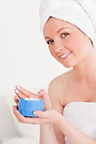 Attractive young woman wearing a towel using skin cream 