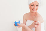 Good looking young female wearing a towel using skin cream