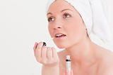 Pretty young woman wearing a towel using a lip gloss