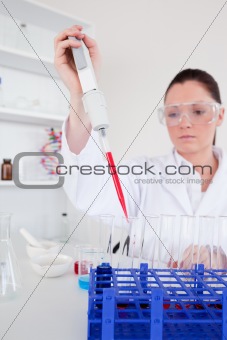 Good looking female biologist holding a manual pipette with samp