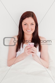 Good looking red-haired woman writing a text on her mobile while