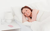 Attractive red-haired woman relaxing while lying on her bed