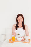 Good looking red-haired woman having her breakfast while sitting