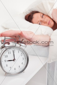 Pretty red-haired female waking up thanks to an alarm clock