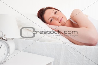 Beautiful red-haired female having a rest while lying on her bed
