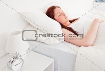 Cute red-haired female having a rest while lying on her bed