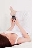 Gorgeous red-haired female relaxing with her mobile while lying 