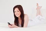 Attractive red-haired female writing a text on her mobile while 