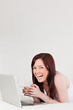 Good looking red-haired female relaxing with her laptop while ly