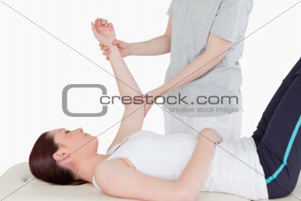 Sportswoman having her arm stretched by a masseuse