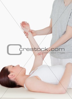 Portait of a sportswoman having her arm stretched by a masseuse