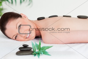 Smiling young woman with massage stones on her back