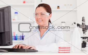 Cute scientist typing a report with her computer