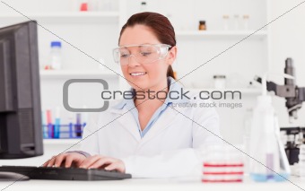 Beautiful scientist typing a report with her computer
