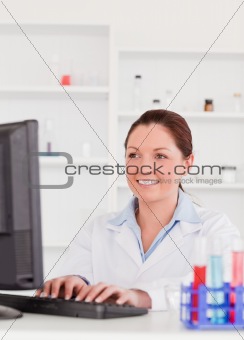 Smiling scientist typing a report with her computer