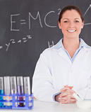 Smilling scientist stanting in front of a blackboard